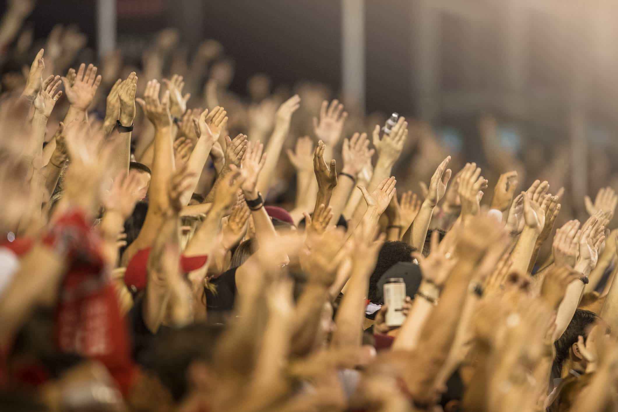 A crowd of people with their hands raised in the air, cheering or clapping at a sporting event or concert.