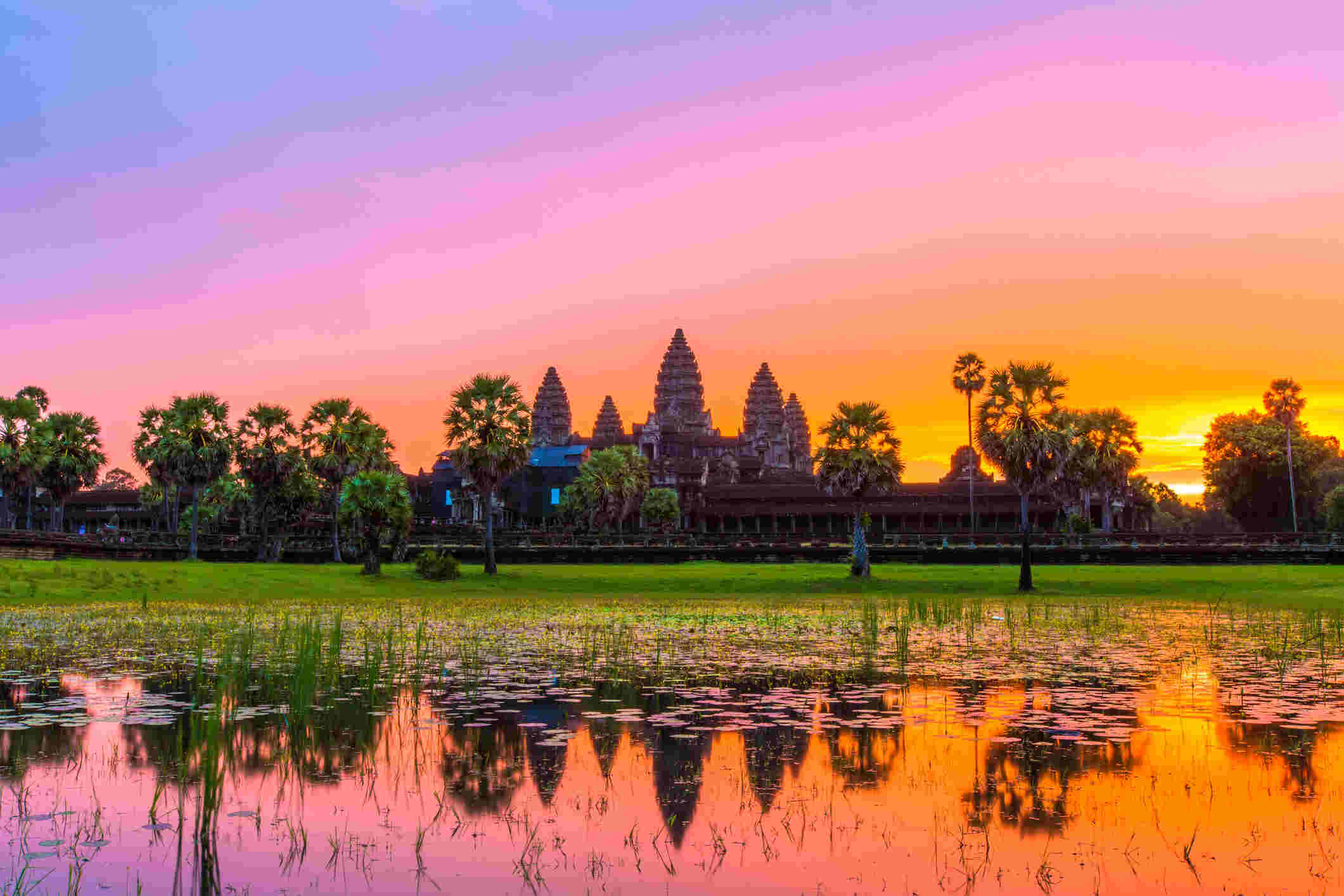 Angkor Wat temple complex at sunrise, reflecting in a calm pond.